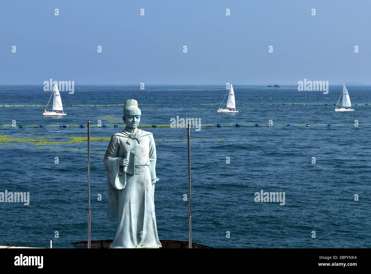 Qingdao. 10 juillet 2025. Une photo de drone prise le 10 juillet 2025 montre la statue de l'explorateur chinois Zheng He et des voiliers participant à un événement de croisière en mer près d'un quai à Qingdao, dans la province du Shandong de l'est de la Chine. Un événement de croisière en mer a eu lieu jeudi dans la ville côtière de Qingdao pour célébrer le 20e anniversaire de la création de la Journée maritime de la Chine et le 620e anniversaire des voyages maritimes de l'explorateur chinois Zheng He. Crédit : Li Ziheng/Xinhua/Alamy Live News Banque D'Images