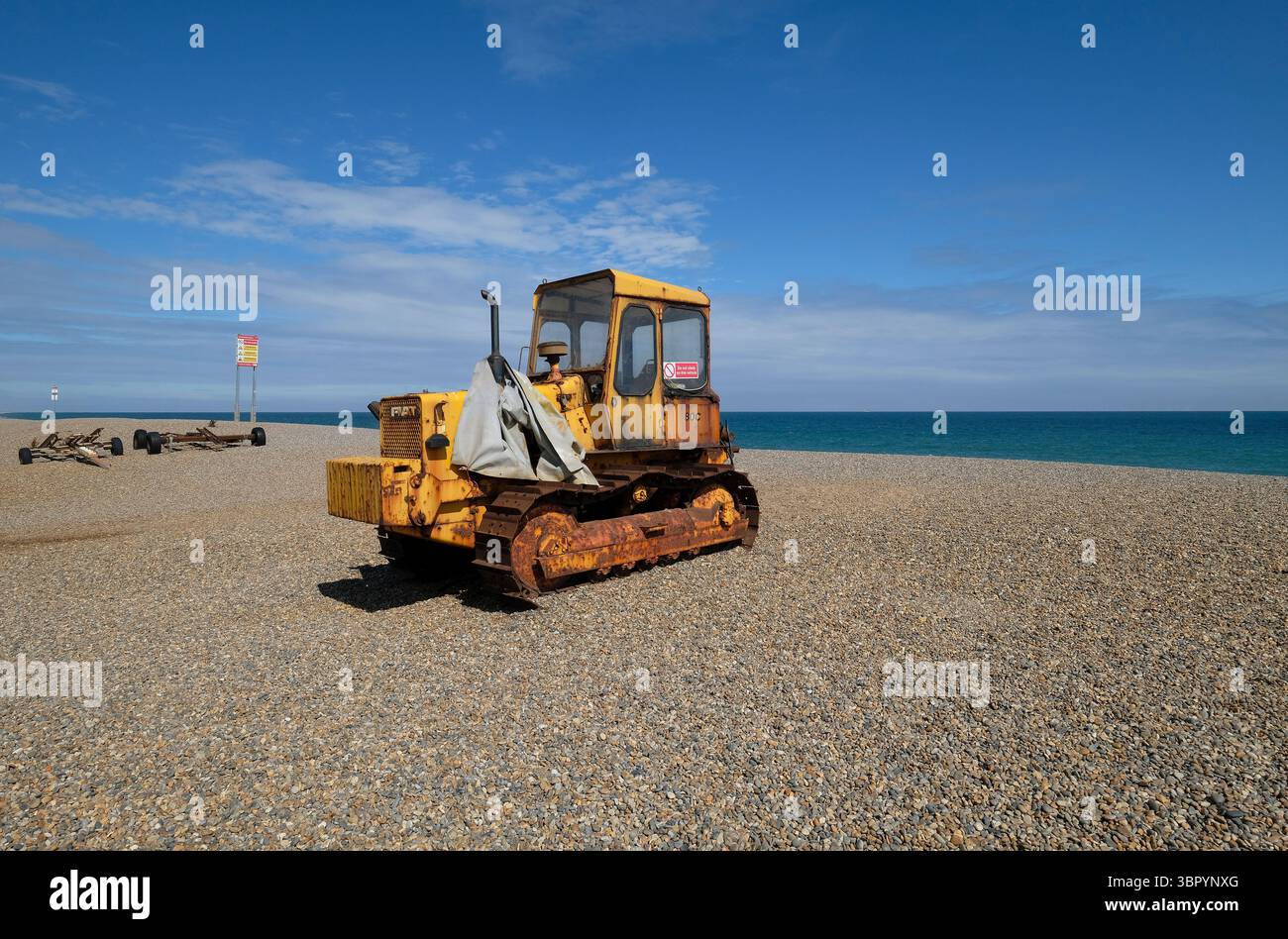 tracteur jaune sur la plage de galets de weybourne, nord du norfolk, angleterre Banque D'Images