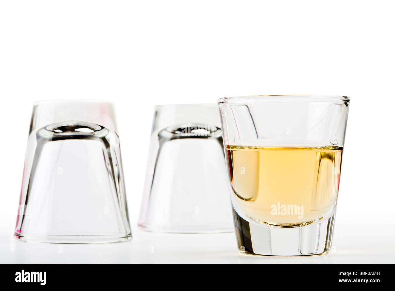 tequila en verre à grenaille avec deux vides en plus isolé sur fond blanc Banque D'Images
