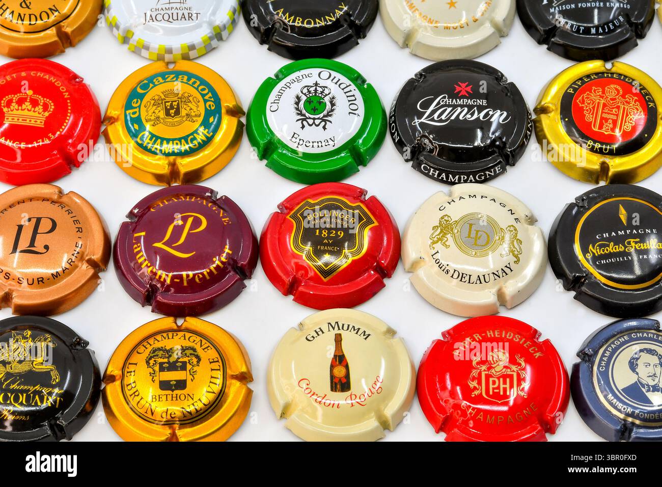 Vue rapprochée des sommets métalliques d'une variété de marques de champagne sur un fond blanc Uni. Banque D'Images