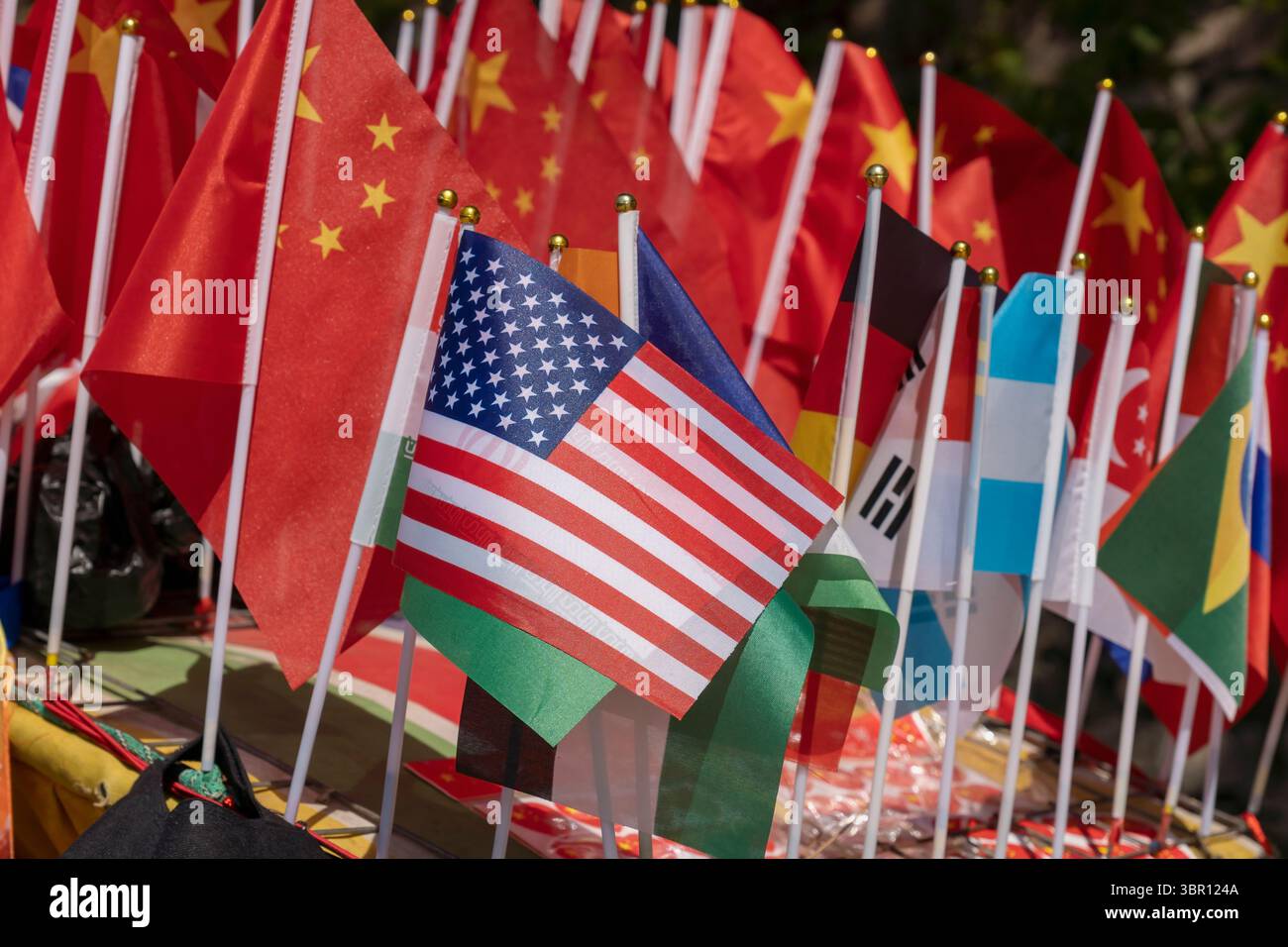 Drapeau américain au premier plan avec des drapeaux chinois et autres sur l'affichage à vendre à un stand de souvenirs, shopping, scène de marché dynamique. Chine - gros plan Banque D'Images