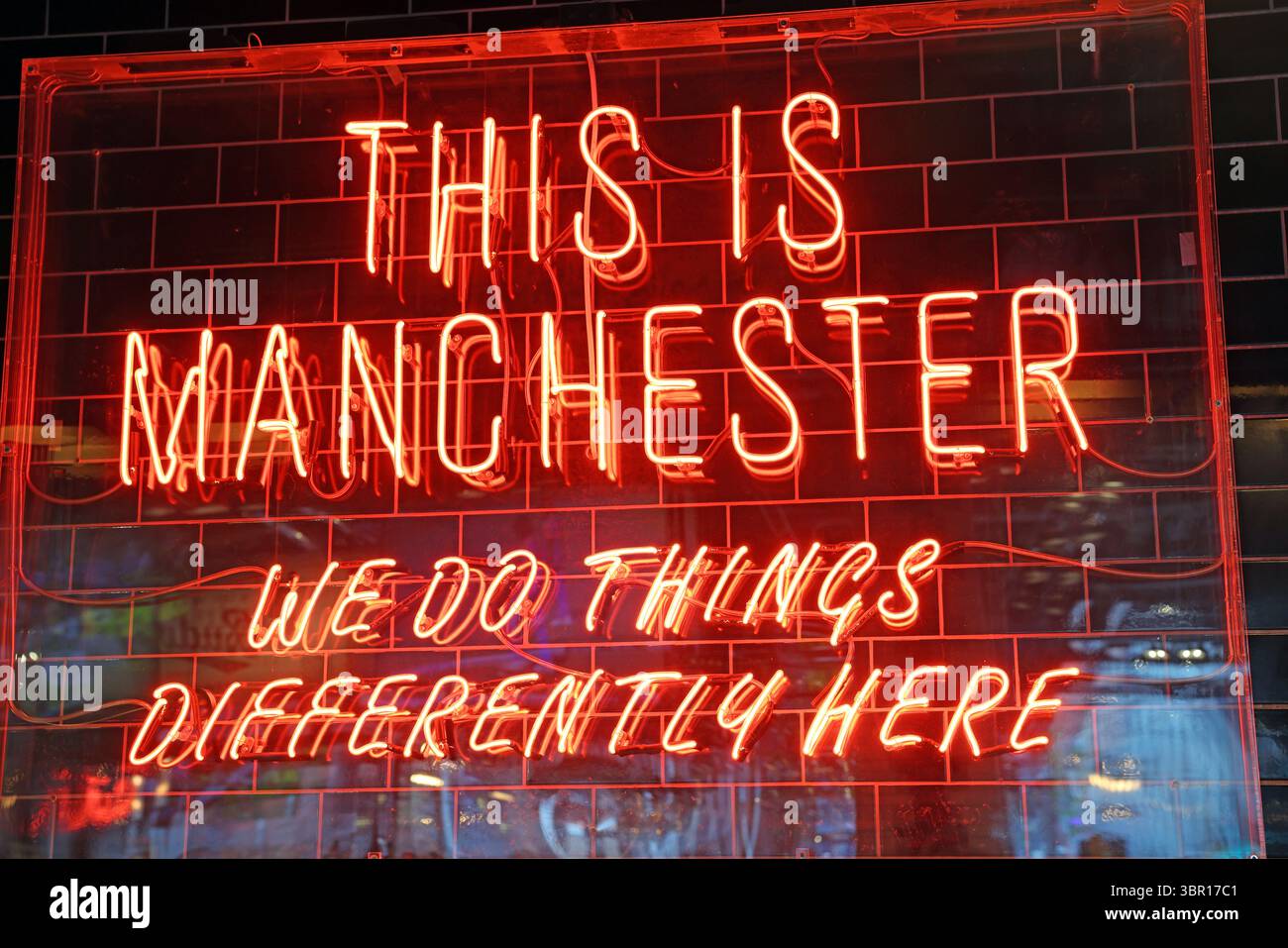 C'est Manchester, citation célèbre, nous faisons les choses différemment ici panneau rouge au néon, centre-ville, Grand Manchester Banque D'Images