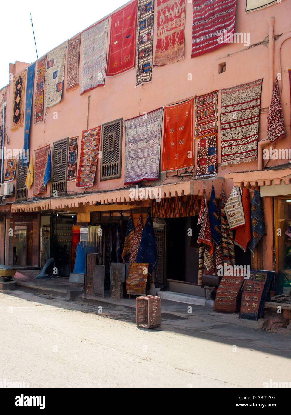 Des tapis et tapis colorés faits à la main sont suspendus à l'extérieur d'une boutique marocaine traditionnelle, mettant en valeur la culture textile artisanale dans un marché local. Banque D'Images