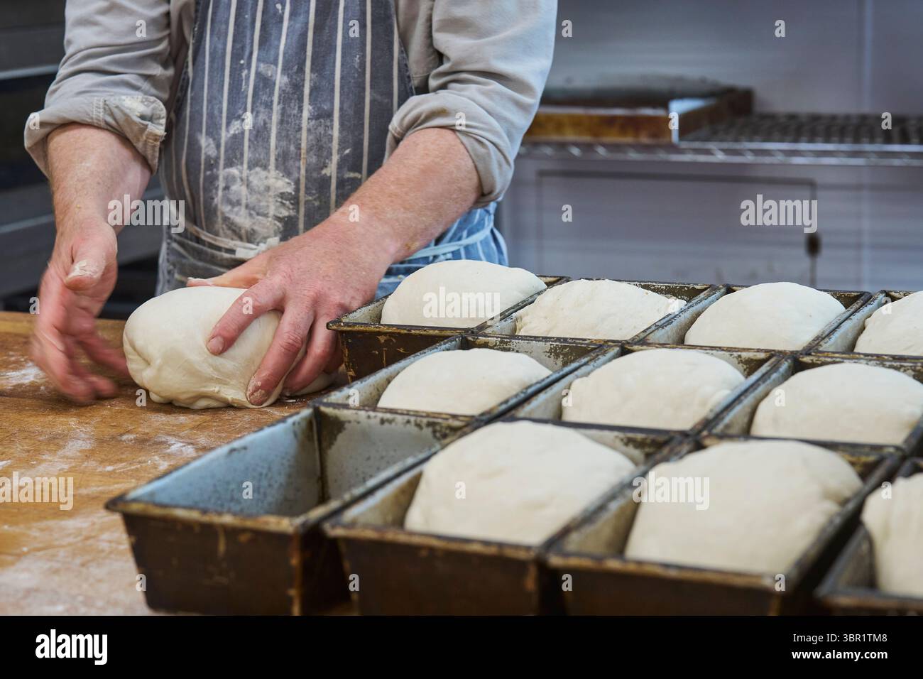Gros plan de la pâte de façonnage du boulanger et de les mettre dans des moules dans la boulangerie Banque D'Images