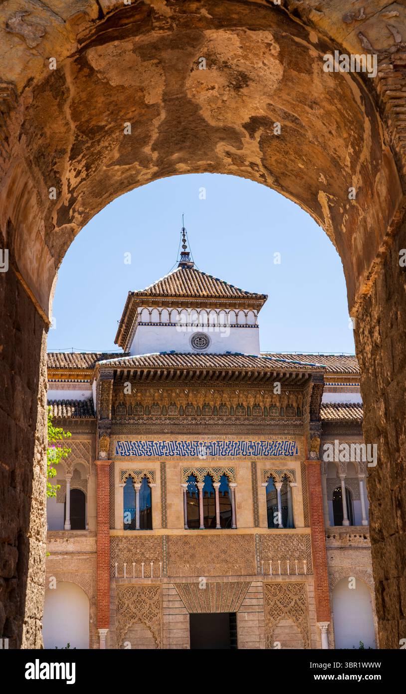 Arche en fer à cheval mudéjar encadrant une frise azulejo ornée et un relief en stuc du Patio de las Doncellas ensoleillé du Real Alcázar de Sevilla Banque D'Images