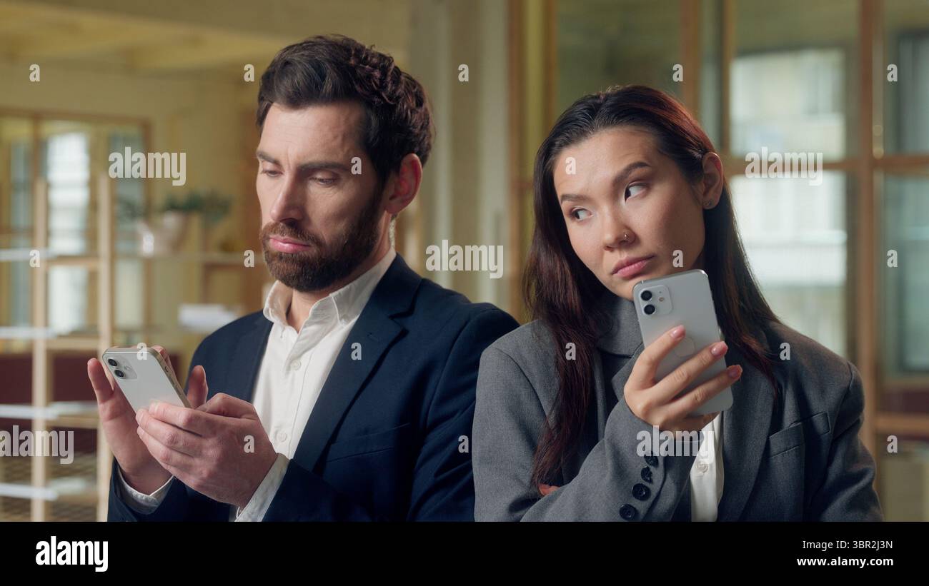 Employés de bureau multiethniques femme d'affaires coréenne homme d'affaires caucasien utilisant le téléphone mobile des collègues d'affaires jetant un coup d'œil aux collègues écran curiosité Banque D'Images