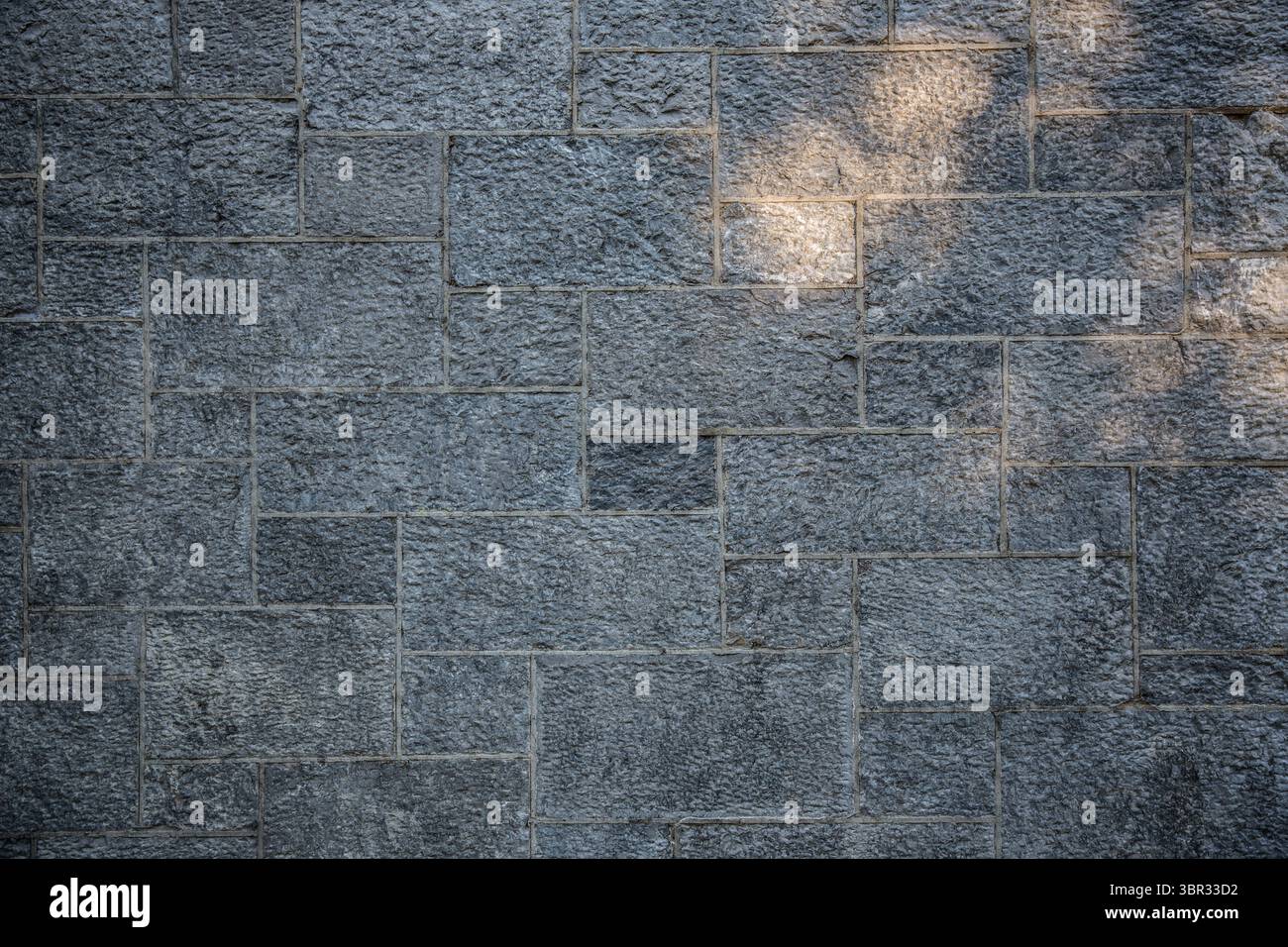 Le mur de blocs de pierre gris texturé est montré dans un design plat, avec des lignes de mortier et la lumière du soleil Banque D'Images Le mur de blocs de pierre gris texturé est montré dans un design plat, avec des lignes de mortier et la lumière du soleil Banque D'Images