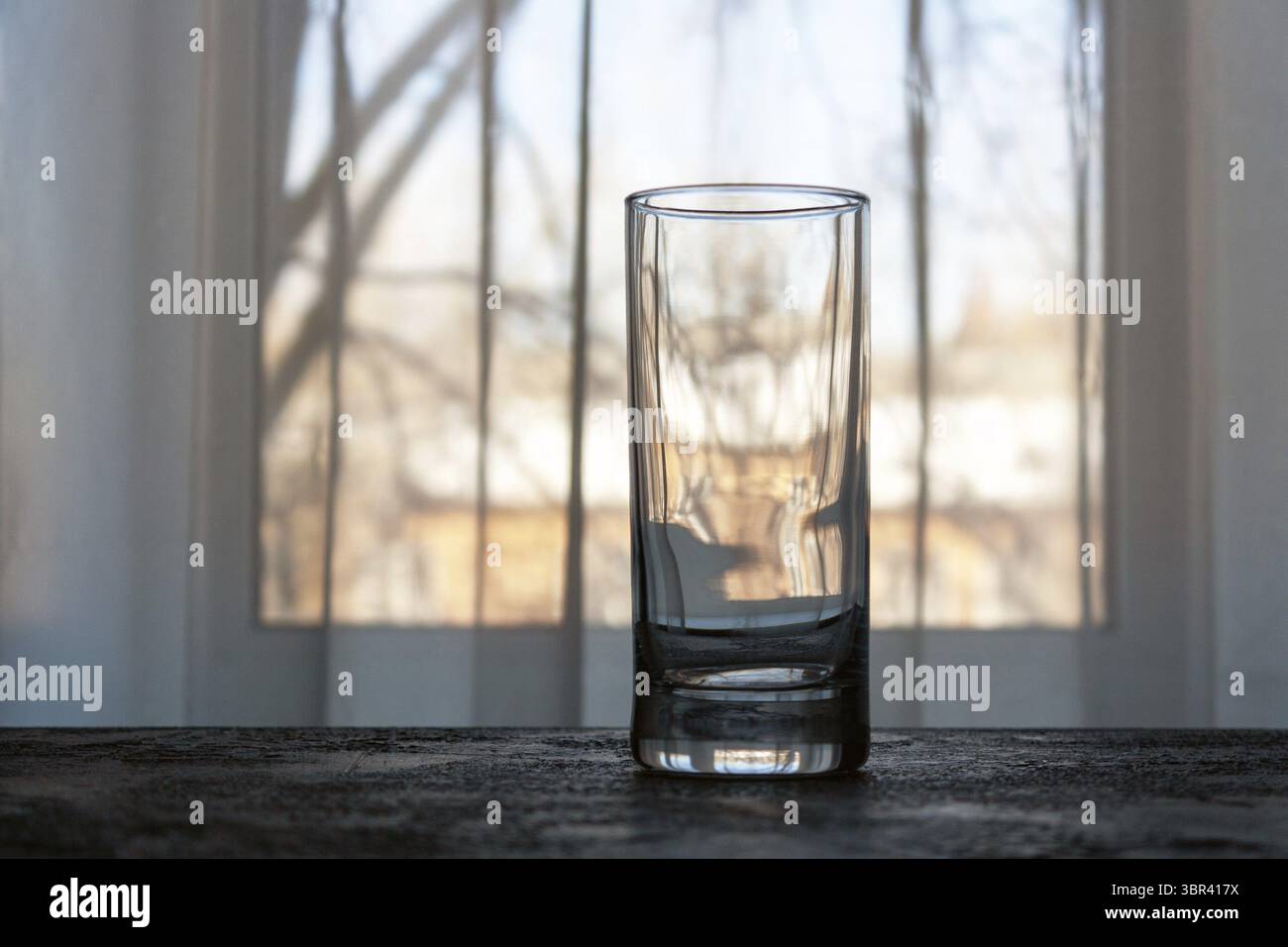 Un verre vide est sur la table contre le fond de la fenêtre Banque D'Images