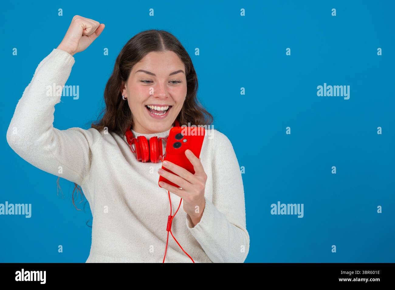 Excité jeune femme célébrant tout en regardant smartphone Banque D'Images