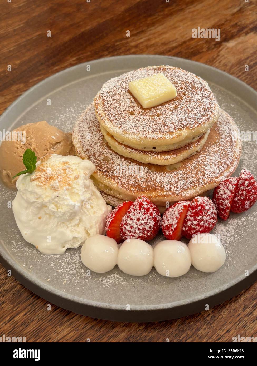 Délicieuses crêpes servies dans une assiette, avec beurre, glace, fraises et boulettes de riz gluantes. Banque D'Images
