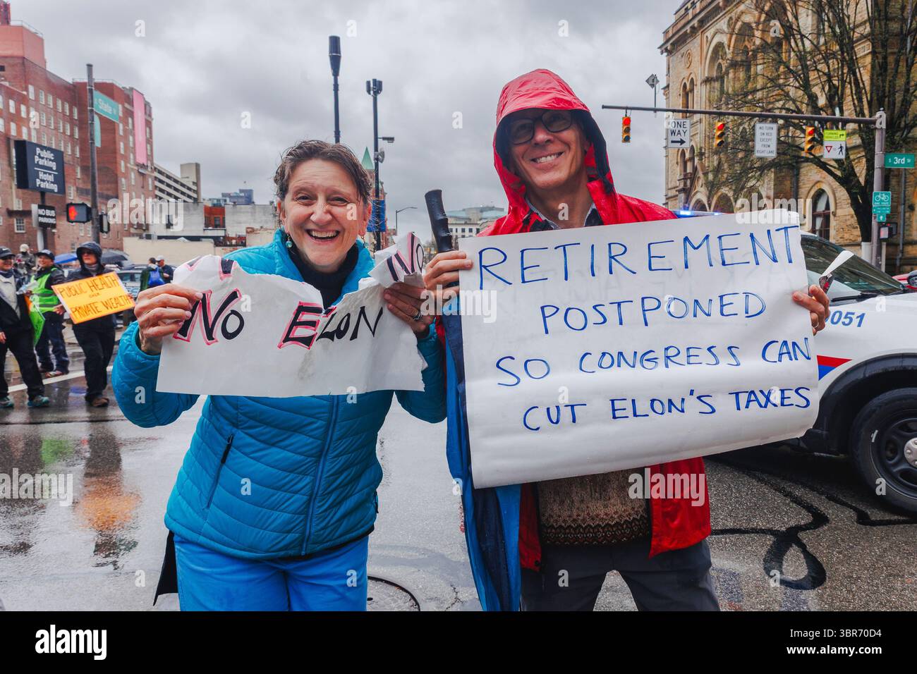 Un couple âgé brandit des panneaux de protestation lors d'un rassemblement sous la pluie Banque D'Images