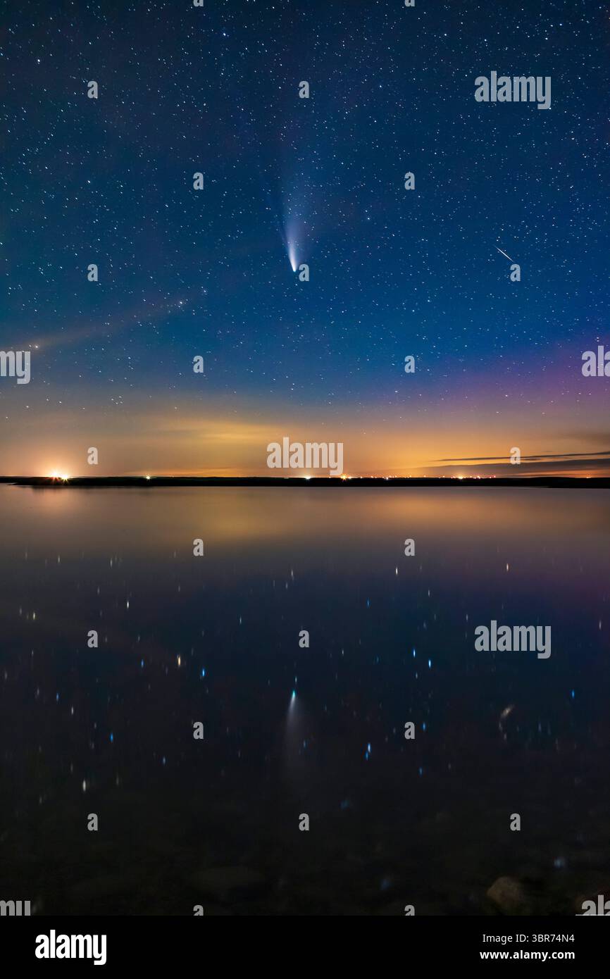 21 juillet 2020, Alberta, Canada : Comet NEOWISE (C/2020 F3) reflétée dans les eaux tranquilles cette nuit du lac Crawling dans le sud de l'Alberta. Une aurore sombre à droite colore le ciel en magenta. Le crépuscule persistant colore le bleu ciel. Un météore ou plus vraisemblablement un satellite en torche apparaît à droite et se reflète également dans l'eau. Même dans cette courte exposition, les deux queues — poussière et ion — sont visibles. C'était le 20 juillet 2020... le contenu principal de l'image est une exposition unique sans suivi de 25 secondes à f/2,8 et ISO 3200 avec l'objectif 35 mm Canon et le Canon 6D MkII. Les nuages lointains, l'horizon et l'eau dedans Banque D'Images