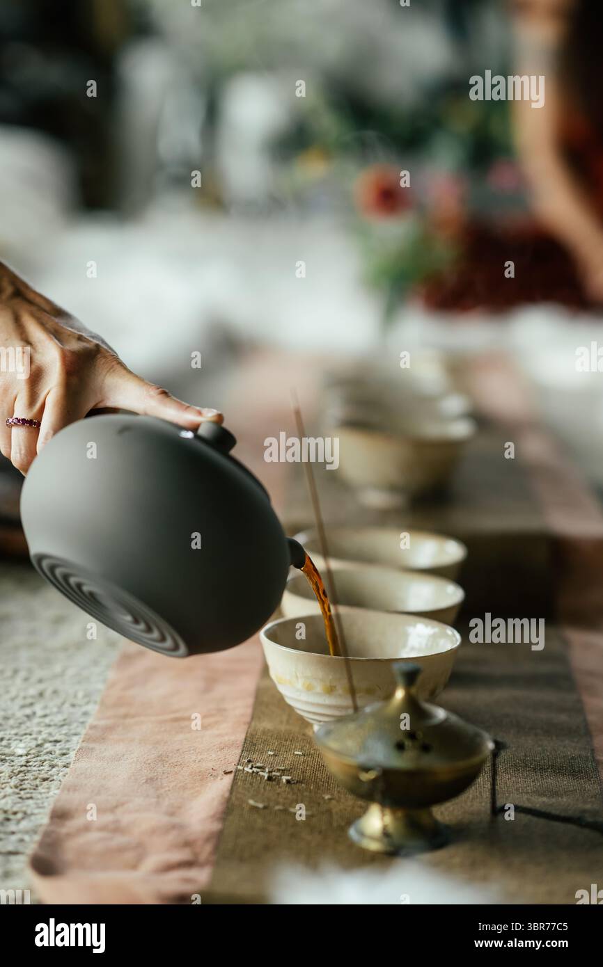 Thé gracieux versé pendant le rituel – tasses en céramique et encens Banque D'Images