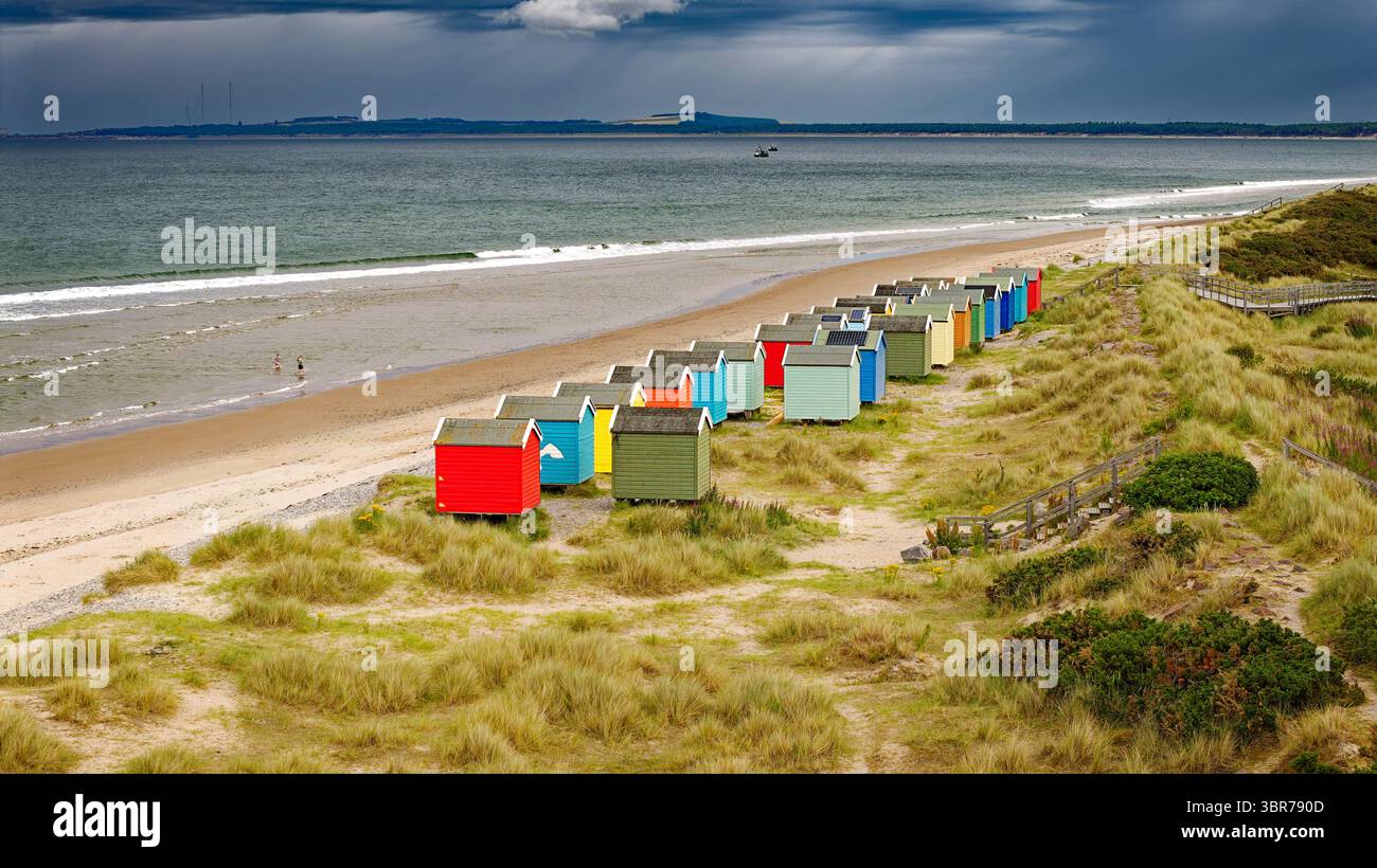 Findhorn Moray Coast Écosse estivale cabanes de plage colorées et les gens dans la mer Banque D'Images
