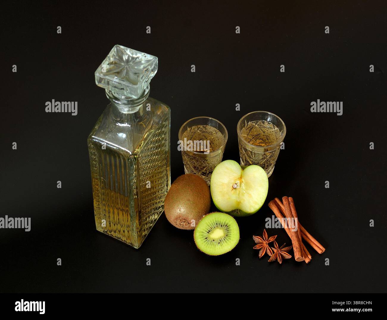 Liqueur de fruits de pomme verte et kiwi avec cannelle et anis sur fond noir. Gros plan. Banque D'Images
