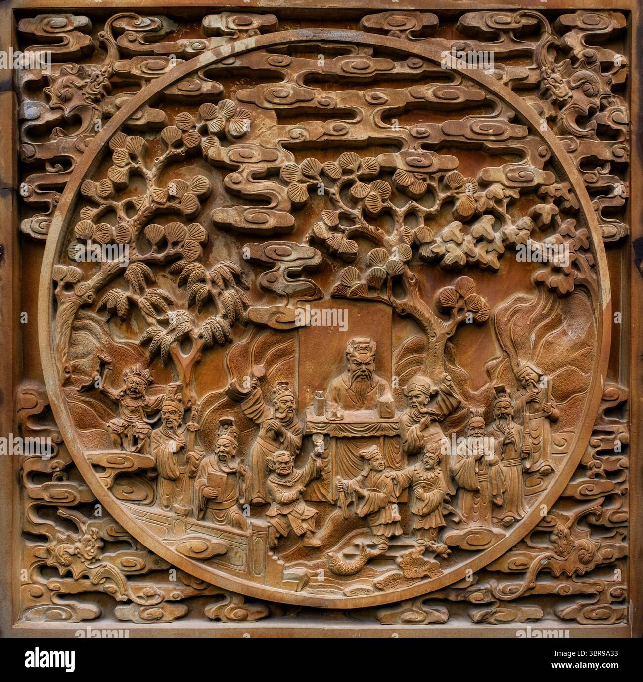 Une scène de sculpture en bas-relief asiatique détaillée avec des figures, probablement narratives dans la nature, disposées dans un paysage d'arbres et de nuages stylisés Banque D'Images