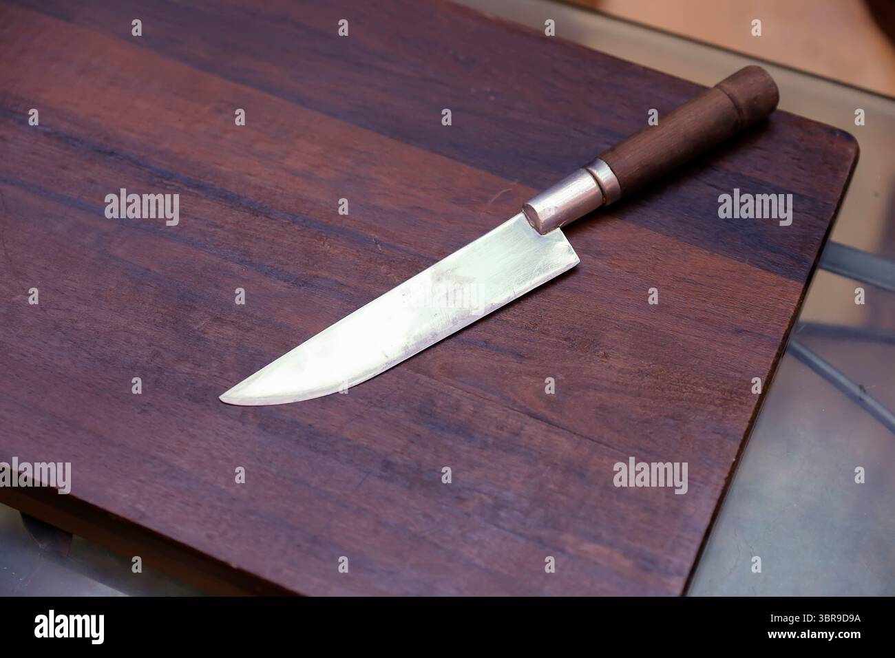 Couteau avec lame brillante sur comptoir en bois, idéal pour une utilisation en cuisine, une coupe précise et un réglage rustique Banque D'Images