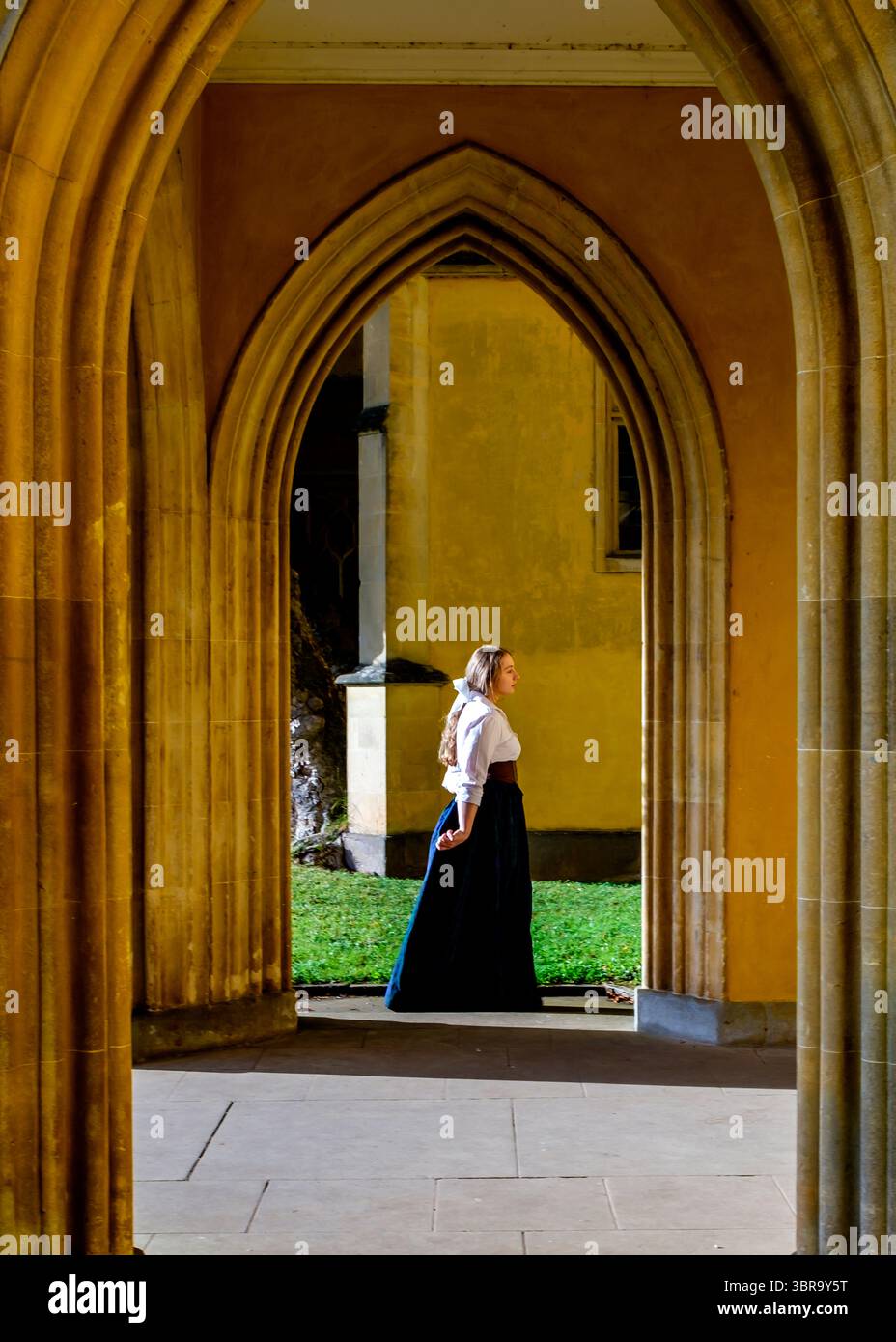 Une femme en vêtements d'époque se tient dans un couloir voûté. Banque D'Images