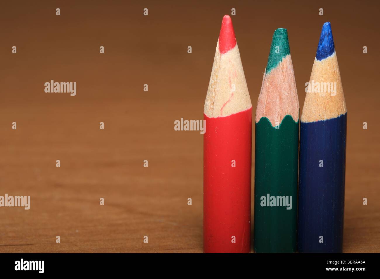 Trois crayons de couleur vibrants attendent d'être utilisés, mettant en valeur de riches teintes de rouge, vert et bleu. Banque D'Images