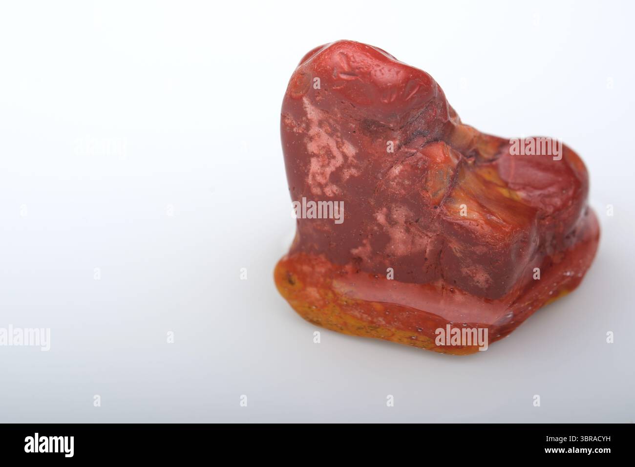 Un minéral rouge frappant se trouve sur une surface lisse, révélant des motifs naturels complexes. Banque D'Images