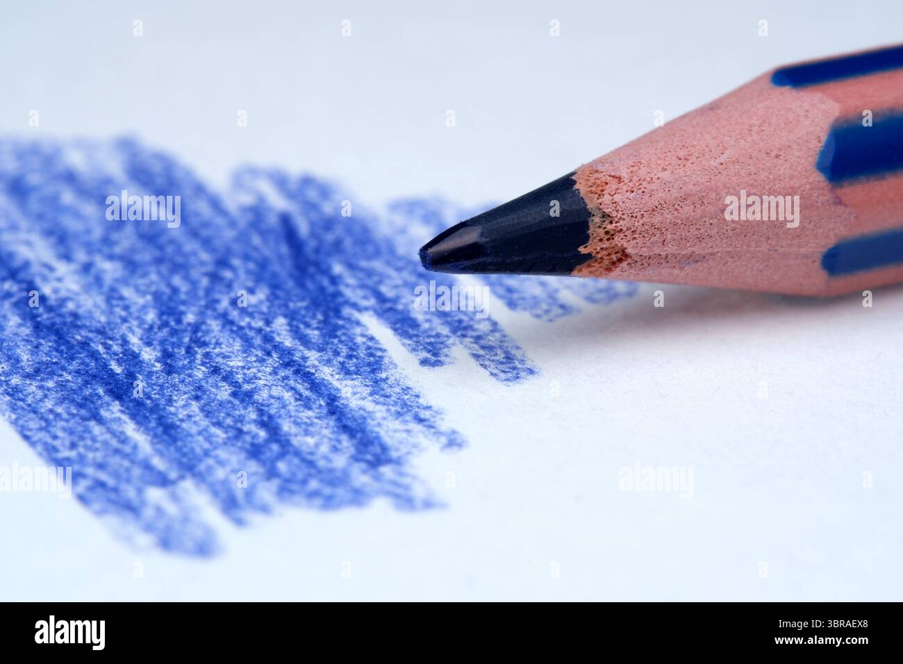 Vue rapprochée d'un crayon bleu faisant des traits vibrants sur du papier. Banque D'Images