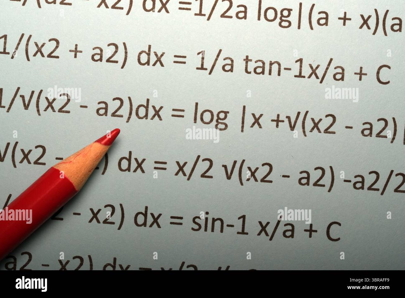 Un crayon rouge met en évidence des équations de calcul complexes sur une feuille bleu clair. Banque D'Images