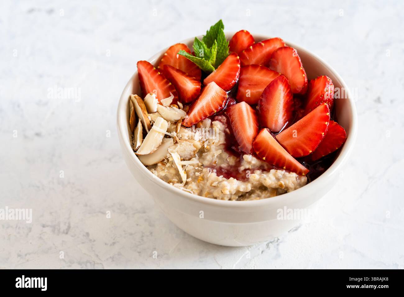 Bol d'avoine multigrain avec fraises fraîches, confiture de baies et noix. Bouillie de petit déjeuner saine Banque D'Images