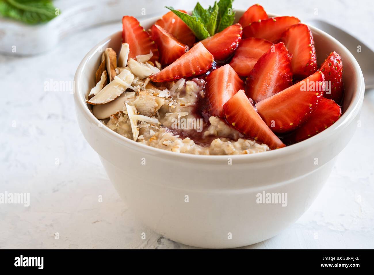 Bol d'avoine multigrain avec fraises fraîches, confiture de baies et noix. Bouillie de petit déjeuner saine Banque D'Images