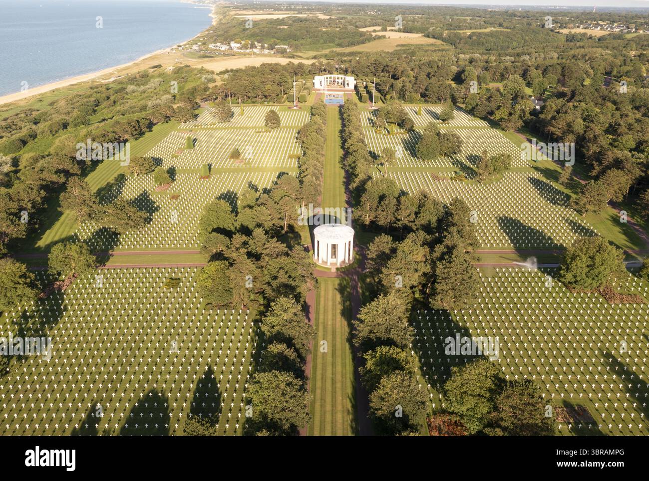 Vue aérienne de rangées de croix blanches s'étendant à travers le paysage verdoyant vers la mer, avec des monuments blancs debout en souvenir solennel, Colleville-sur-mer, Normandie, France. Banque D'Images Vue aérienne de rangées de croix blanches s'étendant à travers le paysage verdoyant vers la mer, avec des monuments blancs debout en souvenir solennel, Colleville-sur-mer, Normandie, France. Banque D'Images