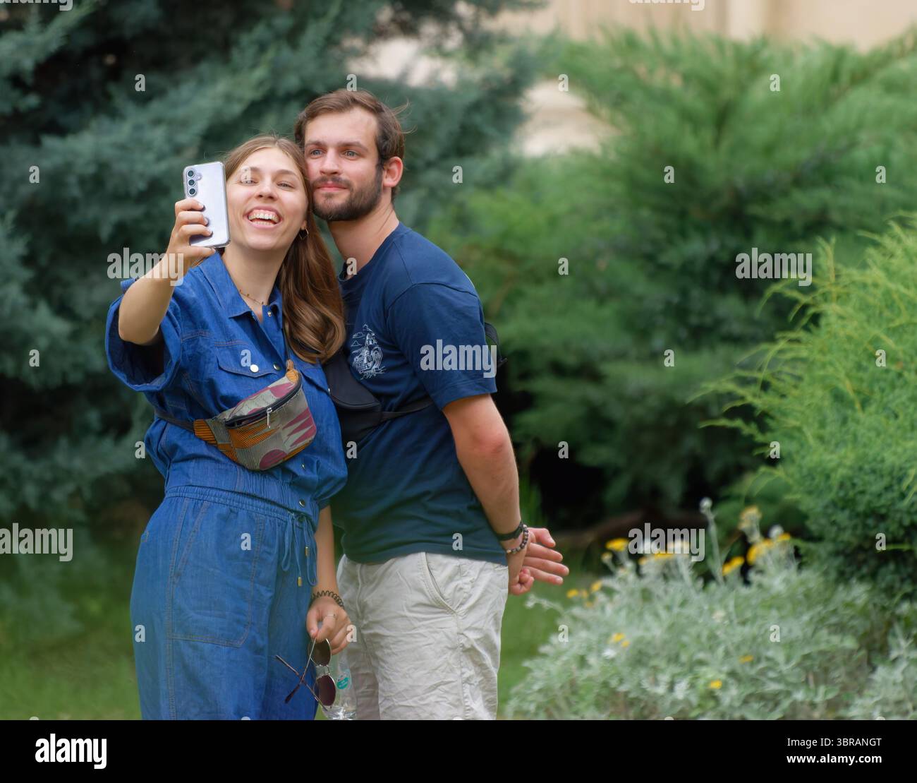 Jeune couple faisant un selfie avec un smartphone dans un jardin Banque D'Images