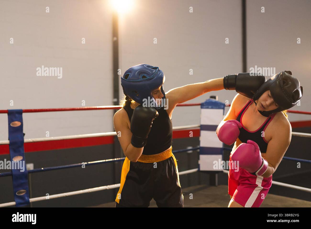 Deux boxeurs féminins qui battent dans un anneau de gymnastique sous des lumières vives portant des gants et des chapeaux, espace copie Banque D'Images