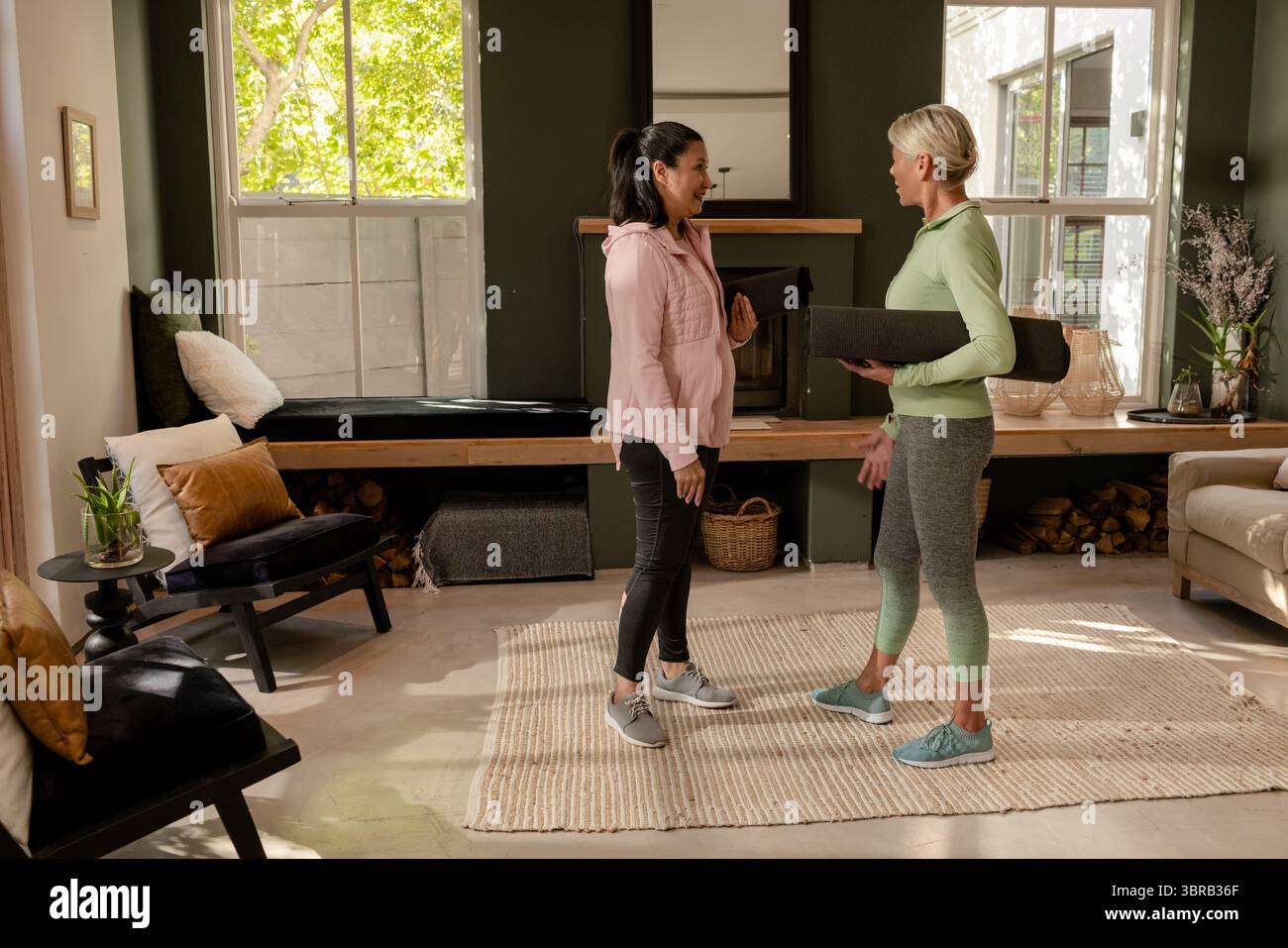 Tapis de yoga roulé repose sur un tapis tissé dans le salon avec mur d'accent vert, cheminée Banque D'Images