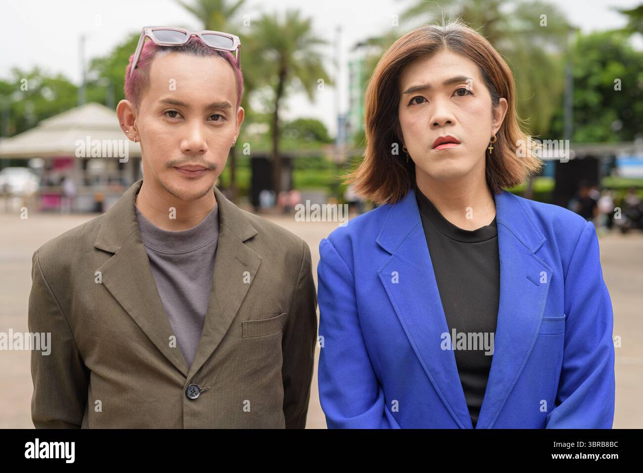 Personne non binaire asiatique confiante avec femme d'affaires transgenre regardant la caméra à l'extérieur dans la ville Banque D'Images