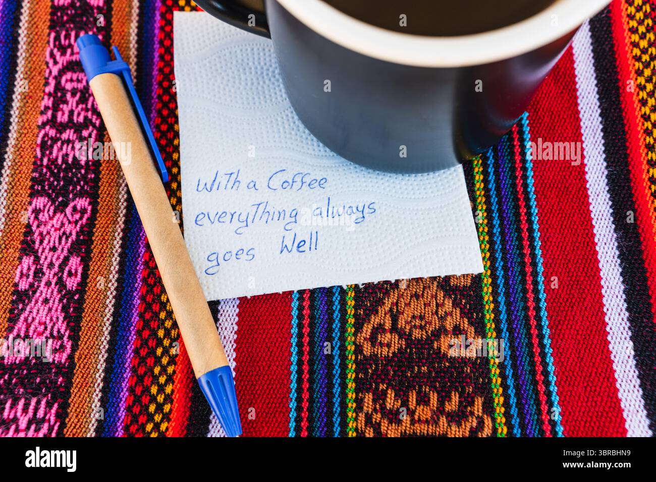 Tasse à café avec une note écrite qui dit avec une tasse de café tout va toujours bien, sur une table colorée avec du tissu inca. Banque D'Images