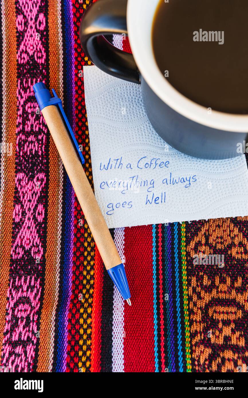 Tasse à café avec une note écrite qui dit avec une tasse de café tout va toujours bien, sur une table colorée avec du tissu inca. Banque D'Images