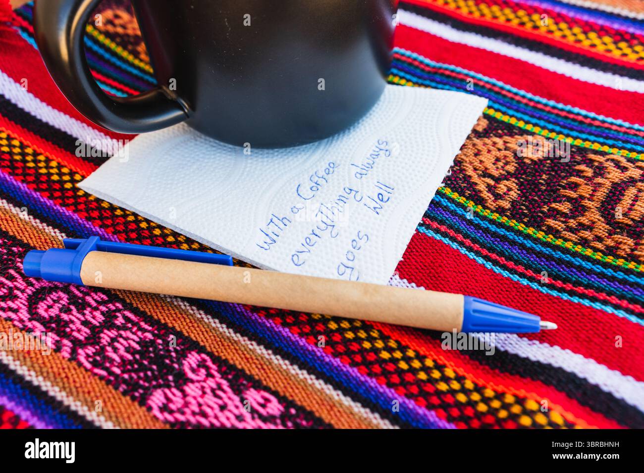 Tasse à café avec une note écrite qui dit avec une tasse de café tout va toujours bien, sur une table colorée avec du tissu inca. Banque D'Images