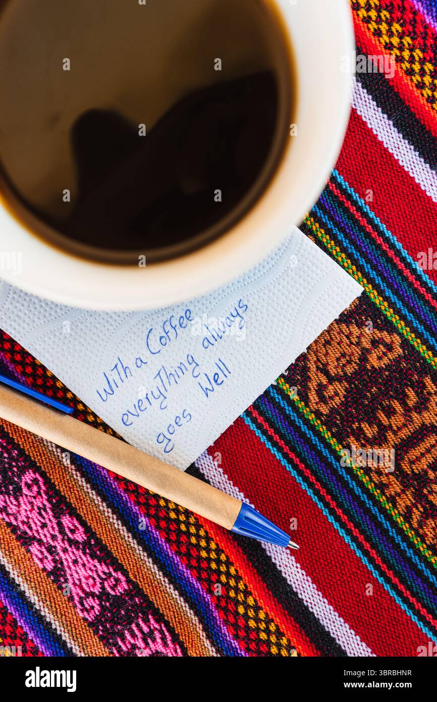 Tasse à café avec une note écrite qui dit avec une tasse de café tout va toujours bien, sur une table colorée avec du tissu inca. Banque D'Images