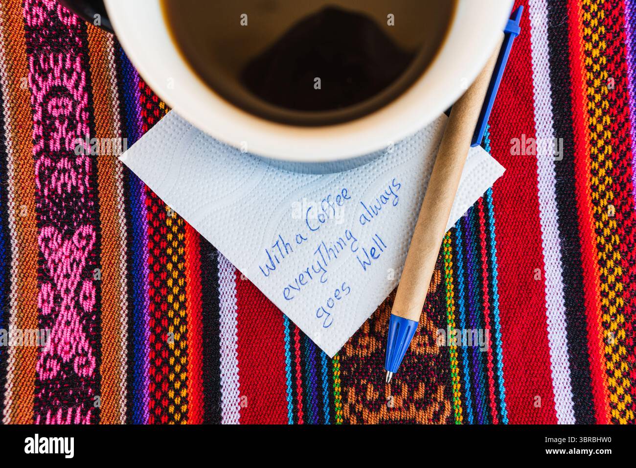 Tasse à café avec une note écrite qui dit avec une tasse de café tout va toujours bien, sur une table colorée avec du tissu inca. Banque D'Images