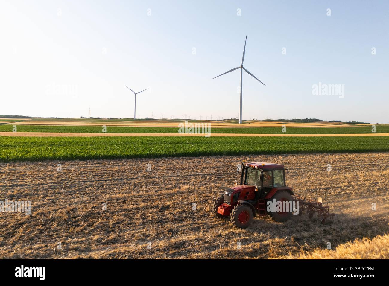Le tracteur agricole travaille sur le terrain avec des éoliennes. Vue aérienne. Banque D'Images
