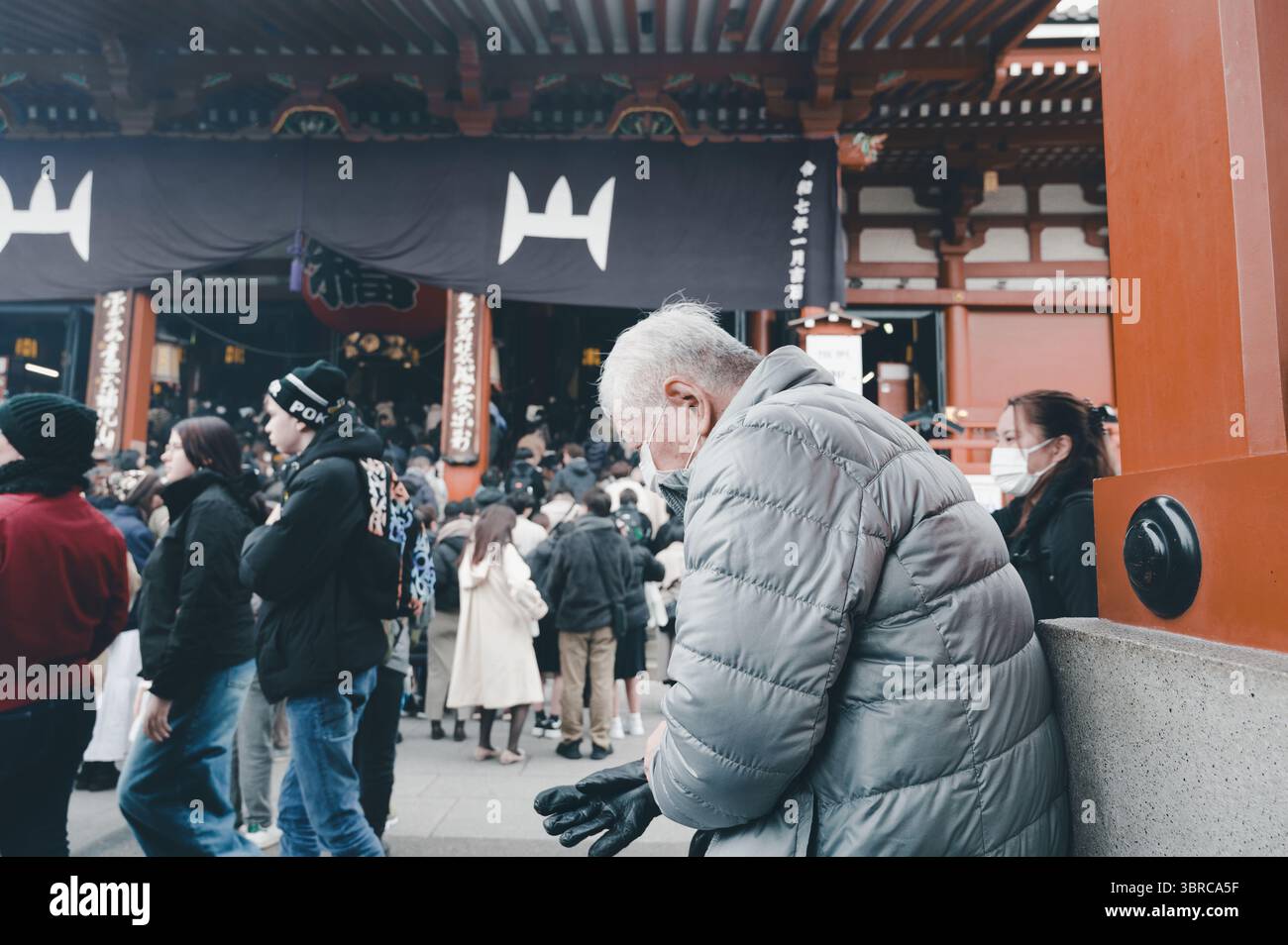 Visiteur âgé prend une pause près de l'entrée animée du temple Senso Ji Banque D'Images