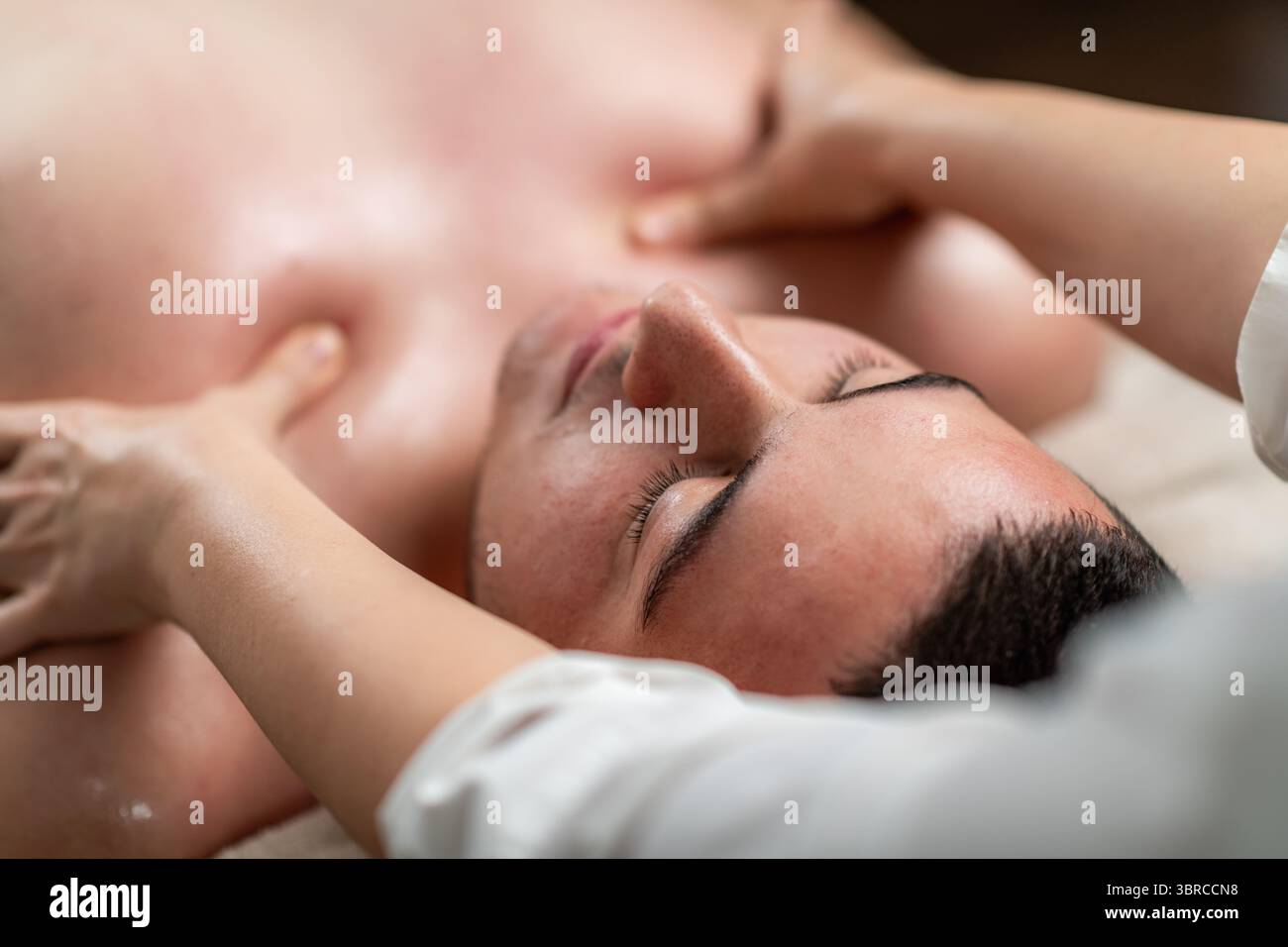 Homme profitant d'un massage relaxant dans un salon professionnel. Banque D'Images