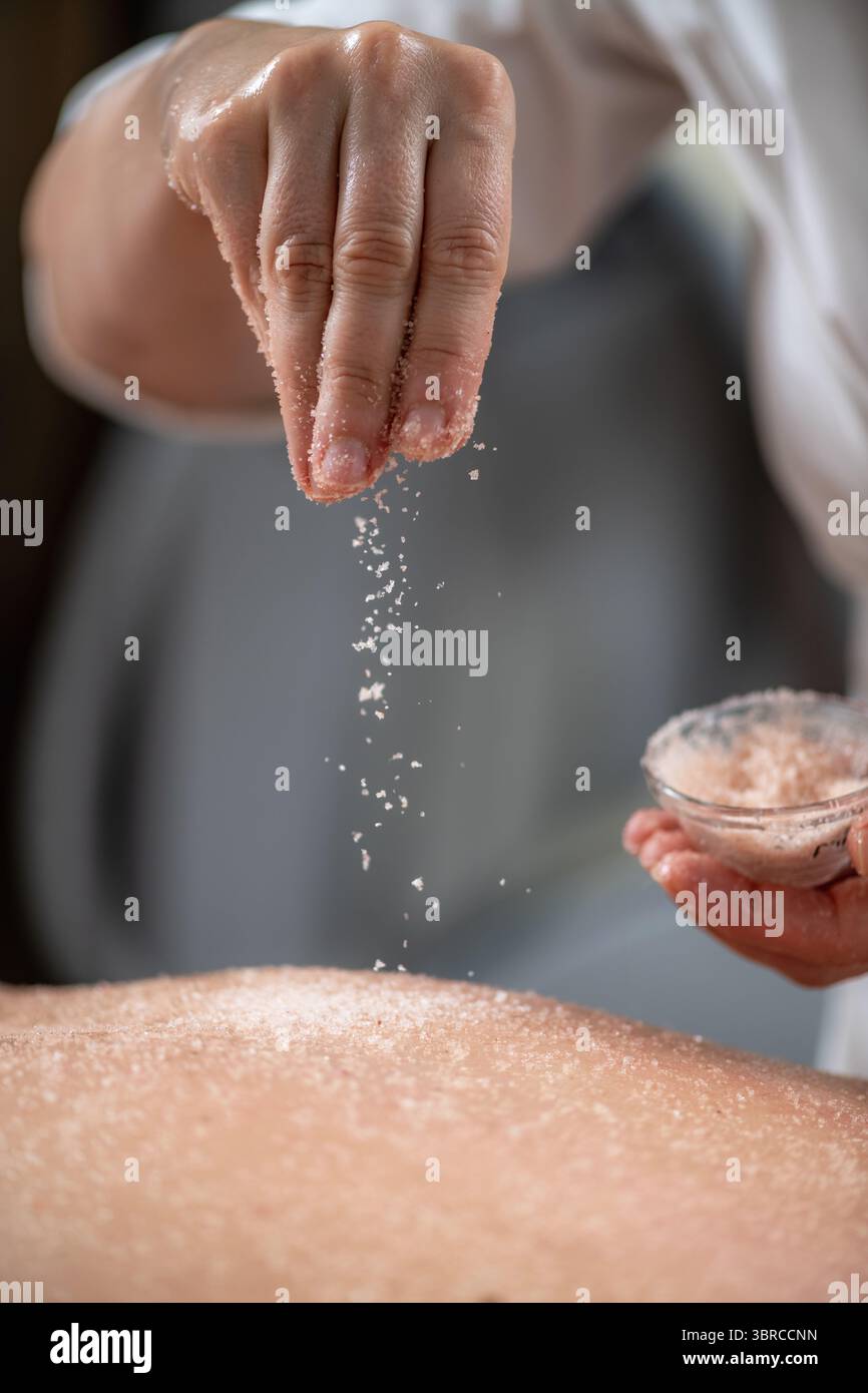 Le massage gommage du dos aux sels exfoliants allie relaxation et revitalisation de la peau, soulageant les tensions musculaires tout en laissant la peau lisse et rajeunie. Banque D'Images
