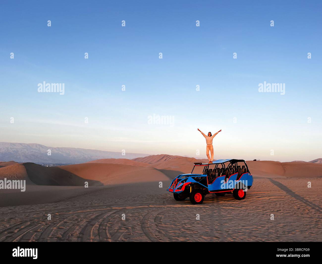 Photo horizontale d'une femme debout sur le toit du buggy, qui conduit les touristes dans la zone désertique, tout en tenant le bras levé et en profitant Banque D'Images