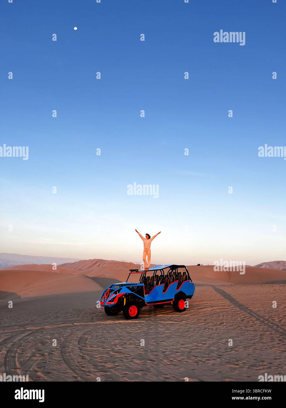 Femme debout sur le toit de buggy, qui conduit les touristes autour dans la zone désertique avec de larges bras levés au-dessus de la tête profitant de la liberté et du paysage o Banque D'Images