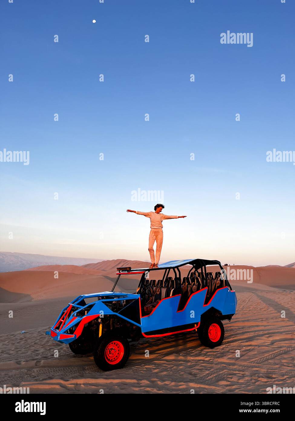Femme debout sur le toit de buggy, qui conduit les touristes dans la zone désertique avec les bras grands ouverts appréciant la liberté et le paysage de Huacachina Banque D'Images