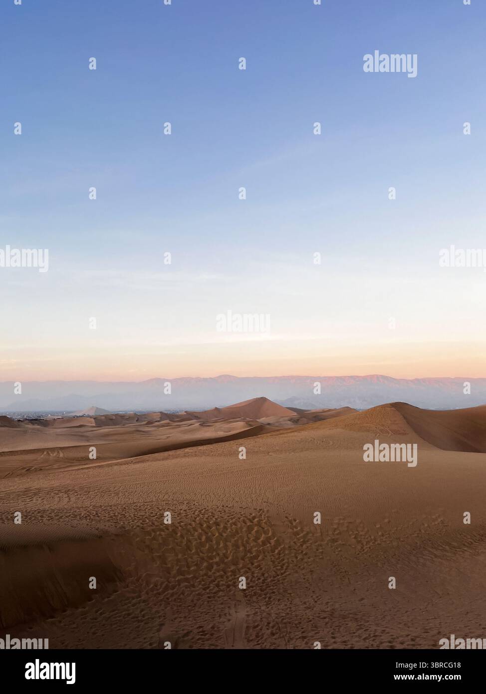 Photo verticale de belles dunes de sable lisses dans un paysage désertique à l'heure du coucher du soleil au lever du soleil. Paysage aride Huacachina, ICA, Pérou. Banque D'Images