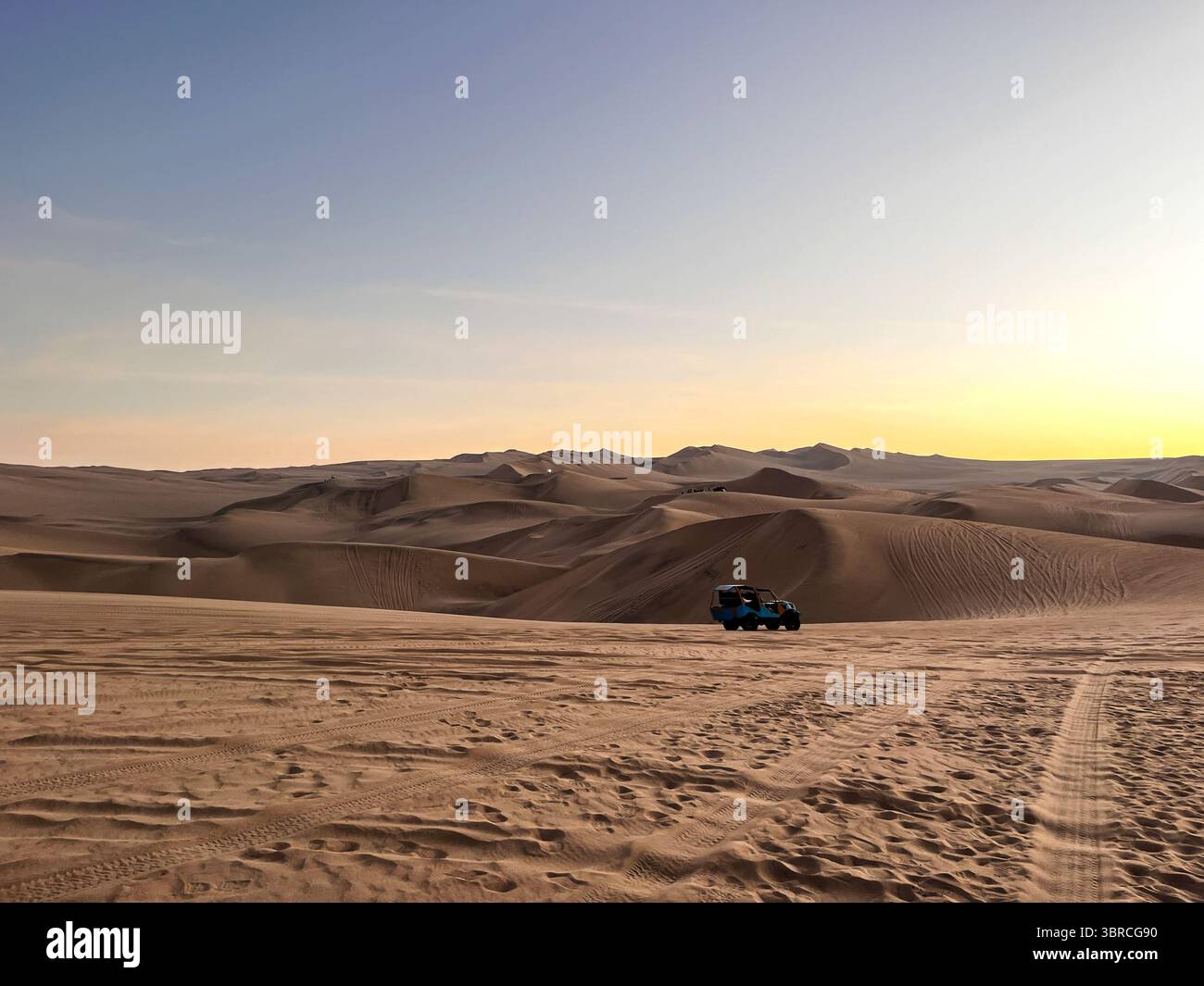 Voiture buggy qui transporte les routes touristiques à travers des paysages arides pleins de rails de pneus et de dunes de sable dans la zone désertique de Huacachina, ICA, Pérou. Banque D'Images
