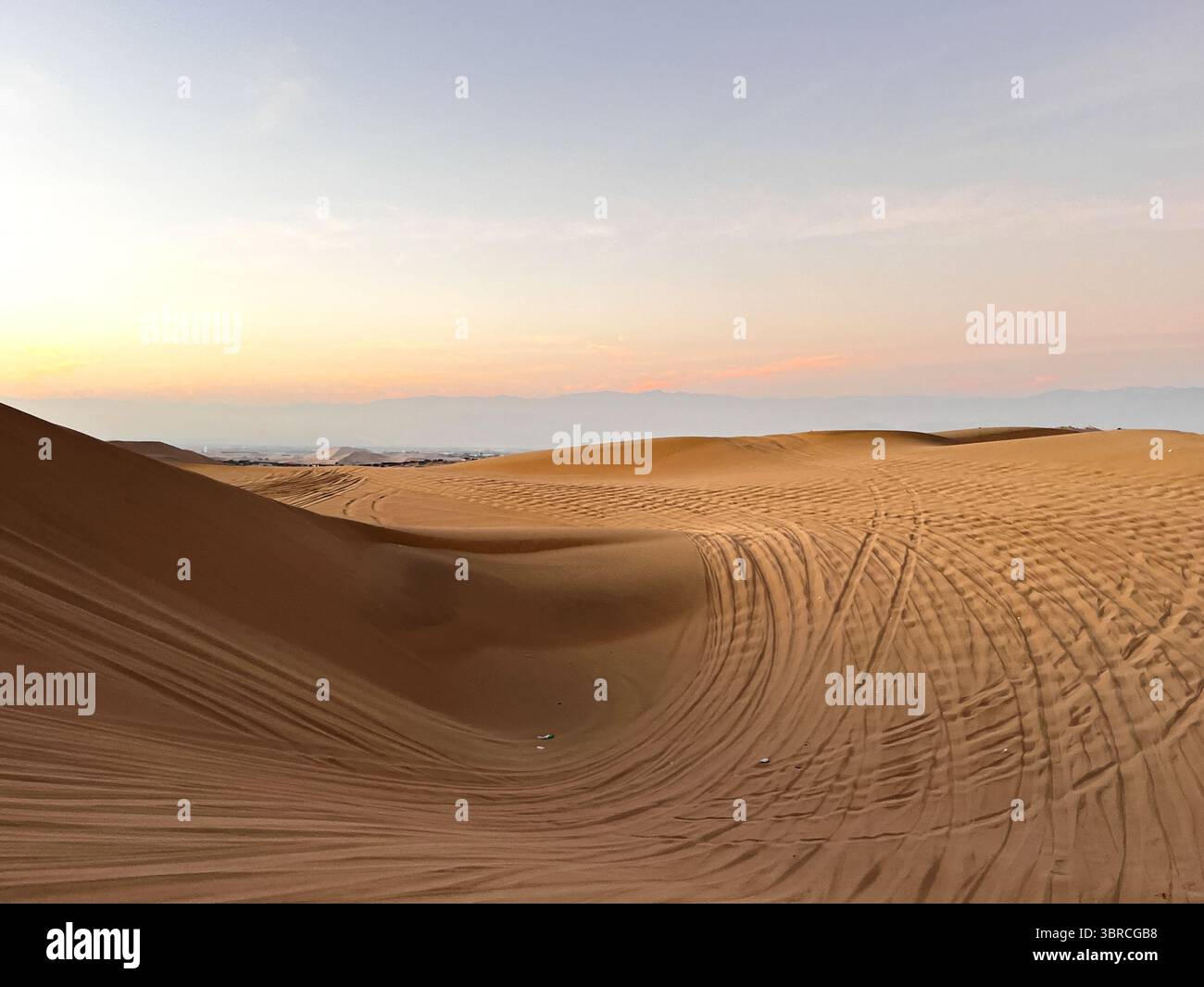 Photo du désert à l'heure du coucher du soleil au lever du soleil avec des traces de pneus de dune buggy dans le sable. Excursions en buggy comme une attraction touristique à Huacachina, ICA, Pérou. Banque D'Images