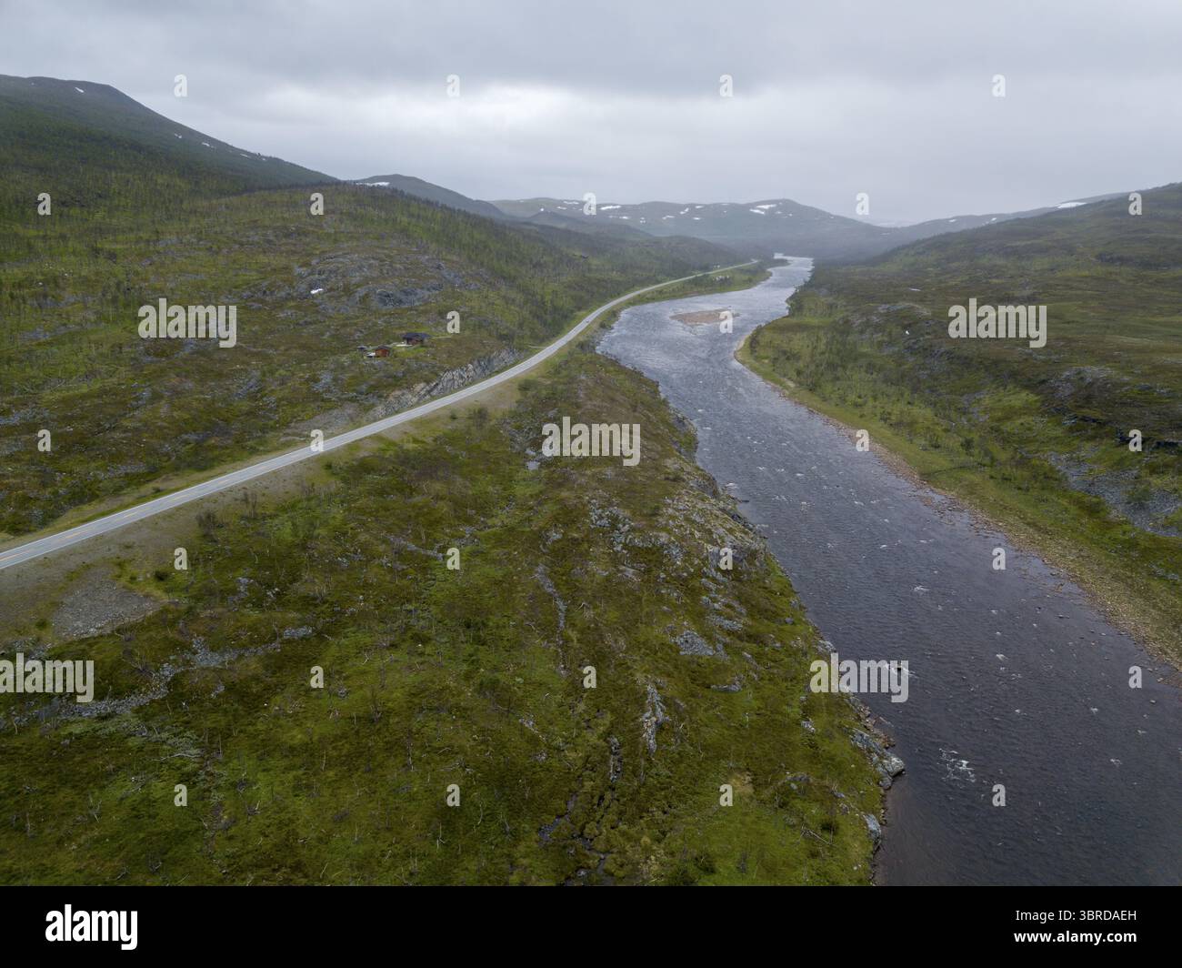 Vue aérienne de la rivière sinueuse serpentant à travers le paysage verdoyant, contrastant avec la route dure coupant à travers le terrain, Karasjok, Finnmark, Norvège. Banque D'Images