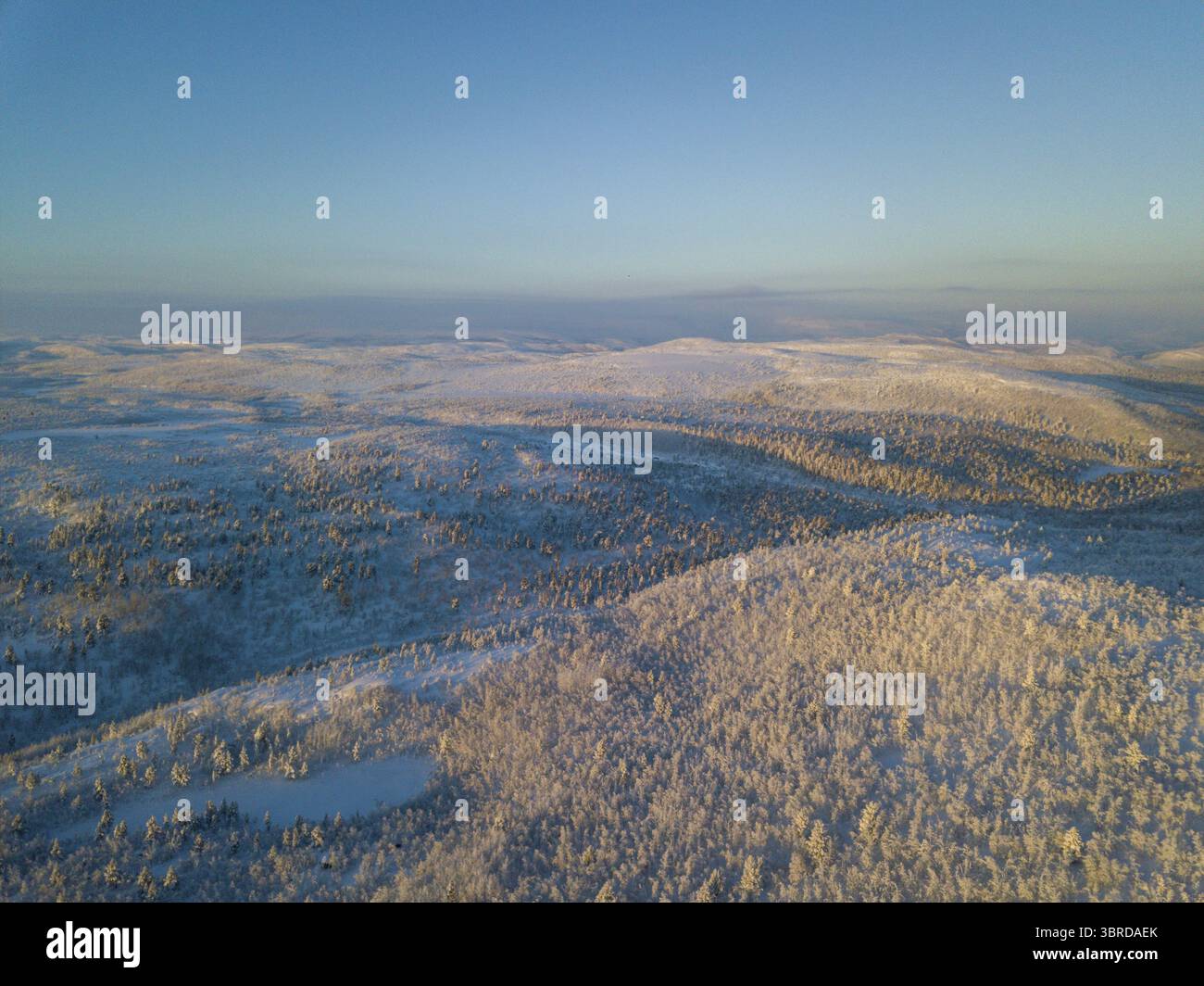 Vue aérienne d'un vaste paysage enneigé où la couverture blanche éclatante contraste avec les ombres, créant une scène hivernale éthérée, Karasjok, Finnmark, Norvège. Banque D'Images